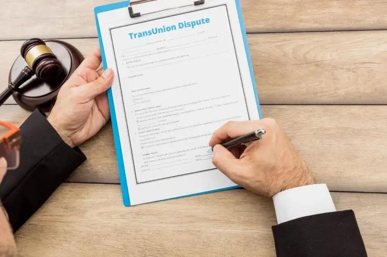 Man sitting behind the desk signing the dispute of TransUnion credit report