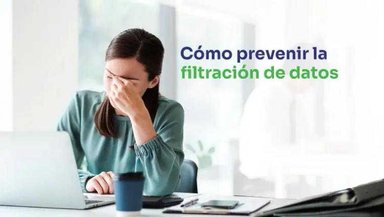 Mujer en la oficina sentada detrás de la computadora portátil llevándose la mano a la cara 