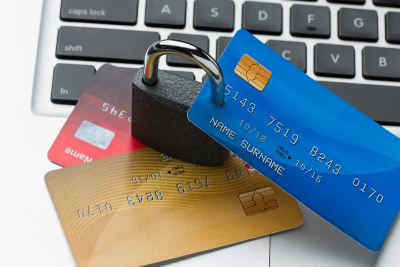 Blue, red and gold credit cards on the lock laying near keyboard