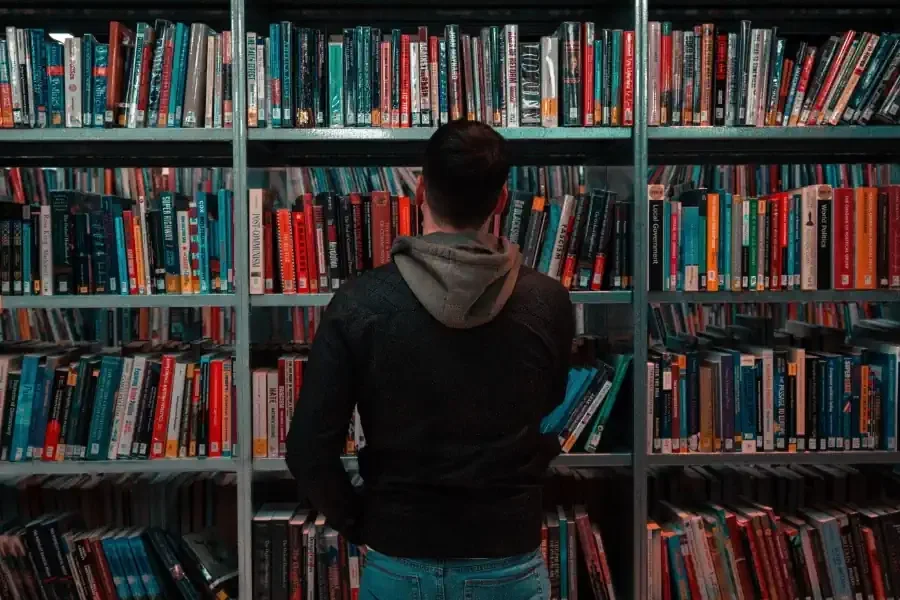 un, hombre, escoger, un, libro, de, un, biblioteca, estante ¿Los libros vencidos de la biblioteca afectan el crédito?