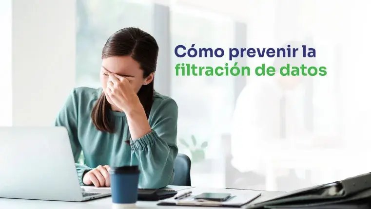 Mujer en la oficina sentada detrás de la computadora portátil llevándose la mano a la cara 