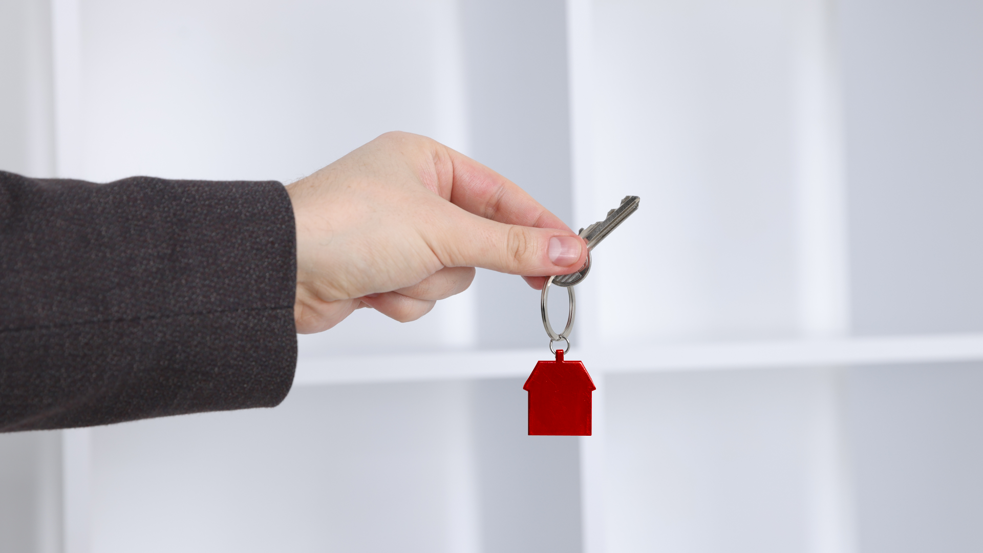 Agentes inmobiliarios: protejan a sus clientes de los errores en la selección | Consumer Attorneys PLLС Imagen de una mano que sostiene la llave de una casa.