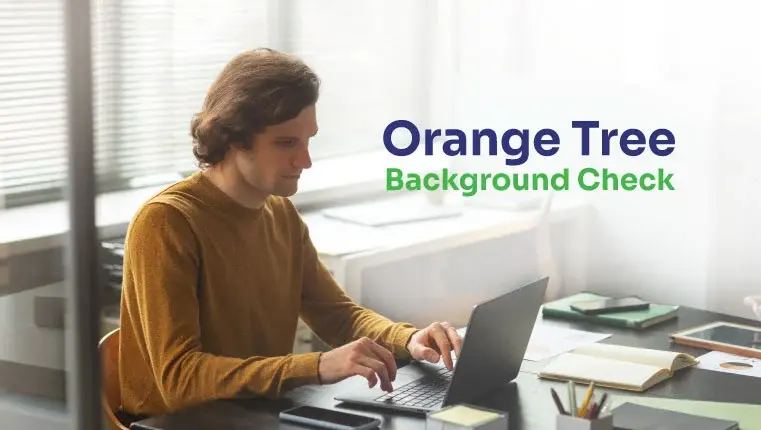 man in a brown sweater sitting behind the laptop